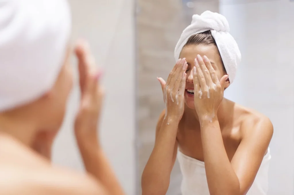 a woman with a towel on her head and hands in front of a mirror